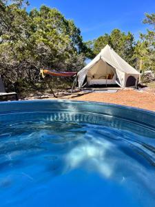 a tent and a swimming pool in front of a camping site at The Juniper Ranch and Retreat in Canyon Lake