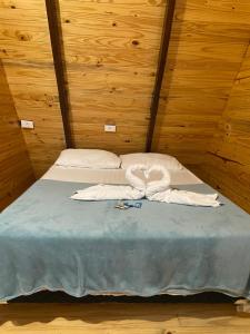 a bed in a wooden room with two towels on it at Chalé São Bento - Lareira, churrasqueira e uma vista incrível para o Vale in Ibicaré