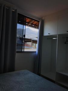 a bedroom with a bed and a window with a view at Casa aconchegante em Catas Altas in Catas Altas