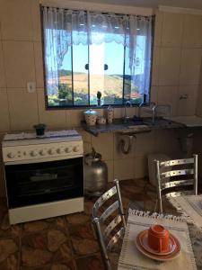 a kitchen with a stove and a sink and a table at Casa aconchegante em Catas Altas in Catas Altas