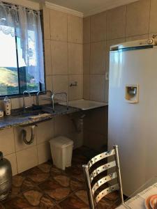 a bathroom with a refrigerator and a sink and a chair at Casa aconchegante em Catas Altas in Catas Altas