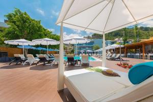 a bed and chairs with umbrellas and a pool at Sunny Days Hotel in Ixia