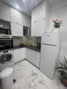 una cucina con armadietti bianchi e frigorifero bianco di White Apartment Athens ad Atene