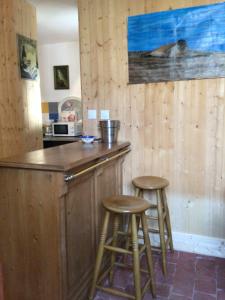a kitchen with two bar stools at a counter at La cabine le Courlis in Le Tréport