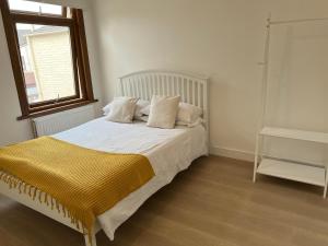 Schlafzimmer mit einem Bett mit weißer Bettwäsche und einem Fenster in der Unterkunft The Leyton Oasis in London