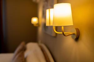 a lamp on a wall next to a bed at The Corner House in Hunedoara