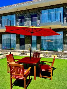 une table rouge avec deux chaises et un parapluie rouge dans l'établissement JA view chalet, à Duwaykhīlah
