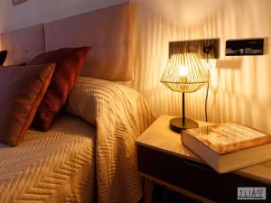 una cama con una mesa con una lámpara y un libro en Villa Eliá, en Arcas