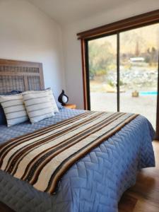 a bedroom with a bed with a large window at Refugio Alma de Montaña, piscina privada in Monte Grande