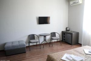 Habitación con 2 sillas, mesa y TV. en Amore Hotel, en Gudauta