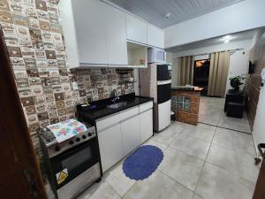 uma cozinha com armários brancos e um tapete azul em Aconchego da Floresta em Angra dos Reis