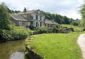 a house next to a river in front of a house at *F2GH* for your most relaxed & Cosy stay + Free Parking + Free Fast WiFi * in Bramley