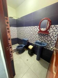 La salle de bains est pourvue de toilettes bleues et d'un miroir. dans l'établissement HOSPEDAJE SCOMIL, à Pucallpa