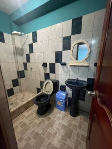 een badkamer met een toilet, een wastafel en een spiegel bij HOSPEDAJE SCOMIL in Pucallpa
