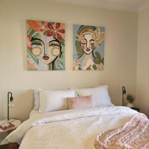 zwei Gemälde über einem Bett in einem Schlafzimmer in der Unterkunft Piper Apartment in Bathurst