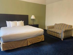 1 cama y 1 silla en una habitación de hotel en The Chateau Bloomington Hotel and Conference Center en Bloomington