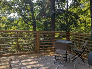 a wooden fence on a deck with chairs and a table at Log Cabin #2 with hot tub deck and sunset view at Loblolly Pines in Eureka Springs