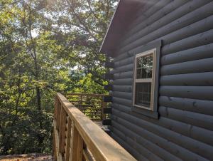 a deck on the side of a house with a window at Log Cabin #2 with hot tub deck and sunset view at Loblolly Pines in Eureka Springs