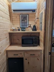a kitchen in a tiny house with a microwave at Log Cabin #2 with hot tub deck and sunset view at Loblolly Pines in Eureka Springs