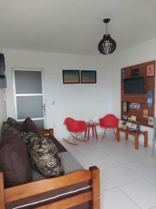 sala de estar con sofá y sillas rojas en Zapipou - Apartamento aconchegante para você aproveitar o melhor de Pipa, en Pipa