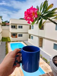 une personne tenant une tasse de café bleu avec une fleur dans l'établissement Zapipou - Apartamento aconchegante para você aproveitar o melhor de Pipa, à Pipa