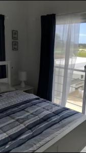 a bedroom with a bed and a large window at Apartamento amueblado en club de playa Nueva Romana in Ahoga Mulo