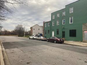 deux voitures garées devant un bâtiment vert dans l'établissement CHRIS LUXURY HOME, à Baltimore