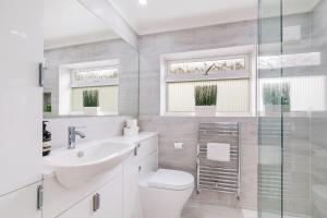 a white bathroom with a toilet and a sink at Luxury 5 BDR 2 BA House with Parking in Sandhurst By 360Stays in Sandhurst +56 photos