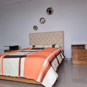 um quarto com uma cama com um edredão laranja e branco em La casita de Vale em Tarapoto