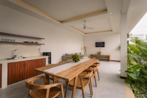 une grande salle à manger avec une table et des chaises en bois dans l'établissement Sari Uma Canggu By Hospitality Bali, à Canggu