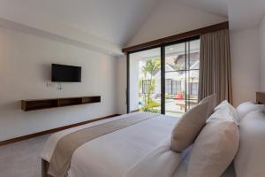 a bedroom with a large bed and a large window at Sari Uma Canggu By Hospitality Bali in Canggu