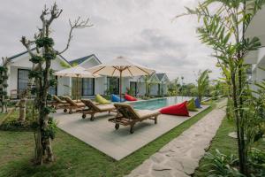 a pool at a villa with benches and umbrellas at Sari Uma Canggu By Hospitality Bali in Canggu