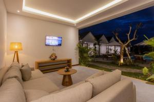 un salon avec un canapé et une télévision à écran plat dans l'établissement Sari Uma Canggu By Hospitality Bali, à Canggu