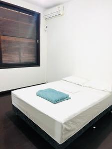 Hostel Jardim de Lotus في بلوميناو: سرير في غرفة بيضاء مع نافذة