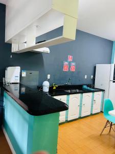 a kitchen with white cabinets and a black counter top at Hostel Jardim de Lotus in Blumenau