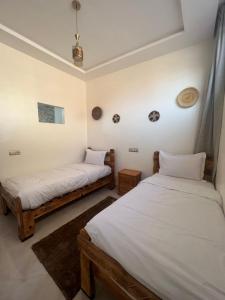 two beds in a room with white walls at Golden WAVE IMSOUANE in Imsouane