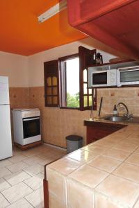 uma cozinha com um lavatório e um fogão forno superior em Logement entier au soleil couchant em Deshaies