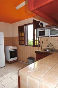 une cuisine avec un évier et une cuisinière four supérieur dans l'établissement Logement entier au soleil couchant, à Deshaies 27 autres photos