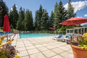 a swimming pool with two chairs and an umbrella at Great Location with Pool and Hot Tub by Harmony Whistler in Whistler