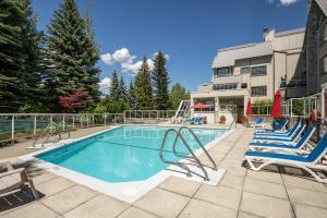 a swimming pool with lounge chairs and a building at Great Location with Pool and Hot Tub by Harmony Whistler in Whistler