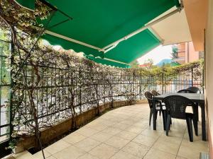 un patio con mesa, sillas y una sombrilla verde en Quadrilocale Free Parking, en Loano