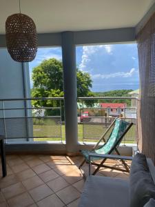 uma varanda com uma cadeira e vista para o oceano em Magnifique appartement à Petit-Havre Le Gosier Guadeloupe em Le Gosier