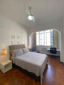 a bedroom with a large white bed and a desk at Tranquilidade in Rio de Janeiro