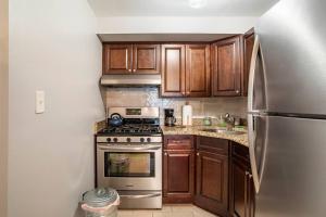 uma cozinha com armários de madeira e um frigorífico de aço inoxidável em Free Access to Manhattan with Free Parking em Tompkinsville