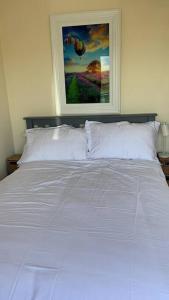 a bedroom with a white bed with a painting on the wall at Elegant Lahinch/ Liscannor Cottage 3B 3BR in Liscannor