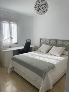 ein Schlafzimmer mit einem Bett, einem Schreibtisch und einer Lampe in der Unterkunft Atuaire Home Sevilla in Mairena del Aljarafe