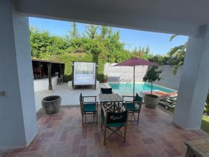 eine Terrasse mit einem Tisch, Stühlen und einem Pool in der Unterkunft Atuaire Home Sevilla in Mairena del Aljarafe