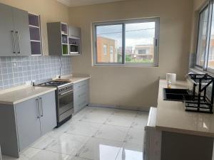 uma cozinha com electrodomésticos brancos e uma grande janela em Luxury for you em Acra
