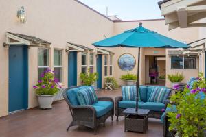eine Terrasse mit Stühlen und einem blauen Sonnenschirm in der Unterkunft Hotel Mac Rae in Avalon