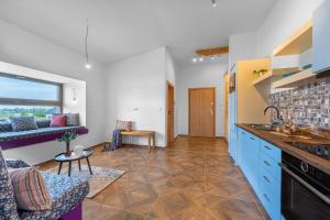 a kitchen with blue cabinets and a living room at LASKARA Garden Apartment by Prague Forest in Nové Jirny